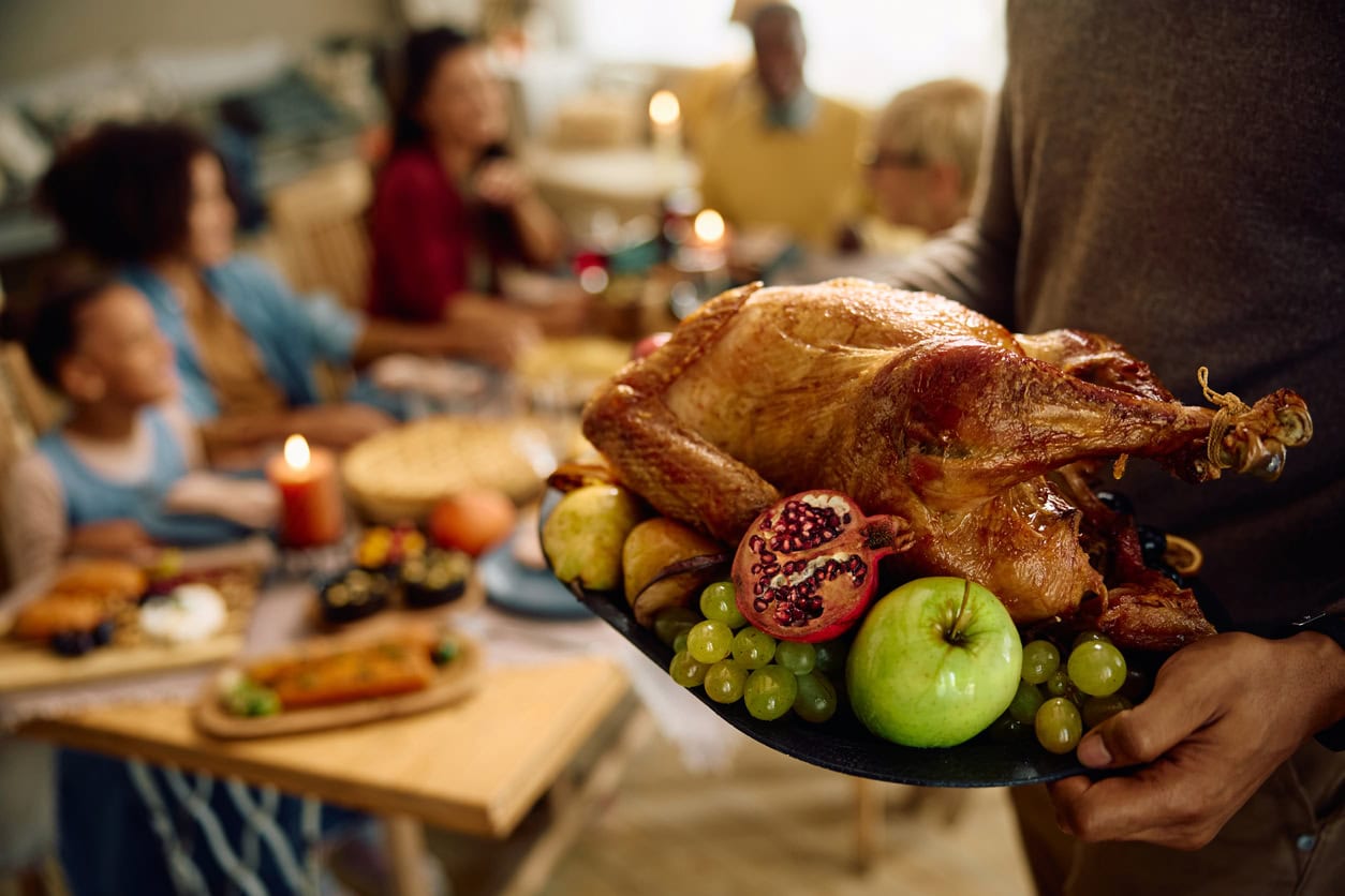 Close up of man serving turkey while having dinner with his family at home.